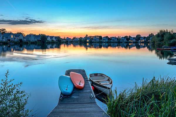 Paddleboards and a boat tied to the jetty at Meadowlark on Summer lake at sunset